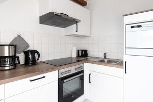 een keuken met witte kasten en een fornuis met oven bij Ferienwohnung Quedlinburg Harz in Quedlinburg