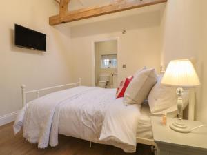 a bedroom with a bed and a lamp and a television at Barn Owl in Ashbourne