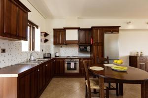 una cocina con armarios de madera y una mesa con un bol de fruta en Kahlua Bay Apartments, en Hersonissos