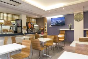 a restaurant with tables and chairs and a tv on the wall at Lille City Hotel in Lille