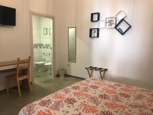 ein Schlafzimmer mit einem Bett und einem Schreibtisch sowie ein Badezimmer in der Unterkunft 40° Parallelo Guest House in Riola Sardo