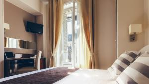 a bedroom with a bed and a window with a desk at Excelsior Opera in Paris