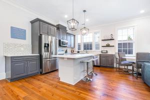 a kitchen with stainless steel appliances and wooden floors at Hosteeva Chic Urban Retreat w Pool Steps to St Charles Ave and Near Bourbon St in New Orleans