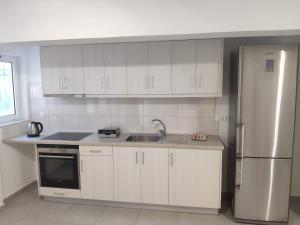 uma cozinha com armários brancos e um frigorífico de aço inoxidável em Alexia Rooms em Káto Palaiokaryá