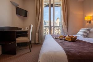 a hotel room with a bed with a table and a desk at Excelsior Opera in Paris