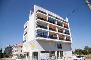 a white apartment building with a car parked in front at The Era Otel in Gölhisar