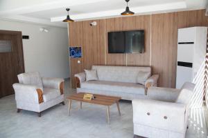 a living room with a couch and two chairs and a tv at The Era Otel in Gölhisar