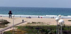 a group of people walking on the beach at Apartamentos turísticos Conil luz in Conil de la Frontera