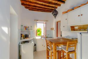 cocina con armarios blancos y mesa de madera en spiti Marcos, en Ano Syros