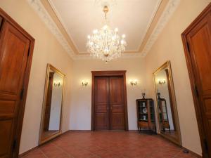 a hallway with a chandelier and a door and mirrors at Schlosshotel Gross Koethel in Hohen Demzin