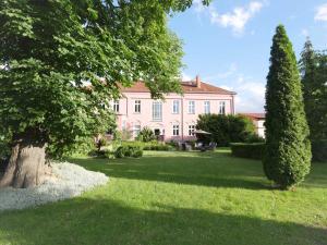 une grande maison rose avec un arbre dans la cour dans l'établissement Schlosshotel Gross Koethel, à Hohen Demzin