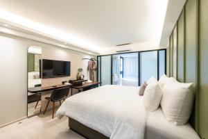a bedroom with a bed and a desk and a television at Kaya Heritage Hotel in Bangkok