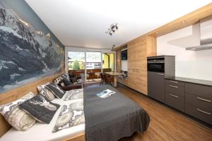 ein Wohnzimmer mit einem Bett und eine Küche in der Unterkunft Alpenstyle Apartment Nina in Kaprun