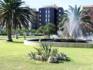 una fontana in un parco con due palme di Hotel Nettuno a Soverato Marina