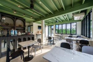 a restaurant with green ceilings and tables and chairs at Kaya Heritage Hotel in Bangkok