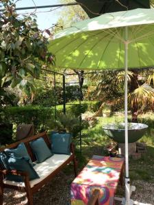 un sofá bajo una sombrilla verde en un patio en B&B delle Arti en Crema