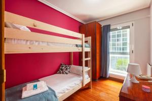 a bedroom with two bunk beds and a red wall at Nafarroa - BasKey rentals in Zarautz