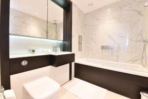 ein Badezimmer mit einer Badewanne, einem WC und einem Waschbecken in der Unterkunft Kew Bridge Apartments in London