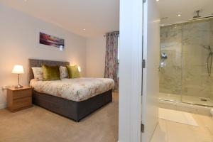 a bedroom with a bed and a glass shower at Kew Bridge Apartments in London
