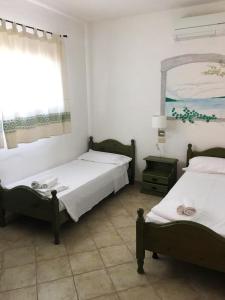 1 dormitorio con 2 camas, ventana y espejo en Vallemare Residence e Studios en Baja Sardinia