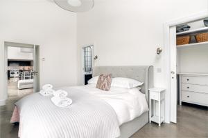 a white bedroom with two beds with towels on them at The Cart Shed in Laurencekirk