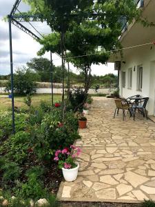 een patio met bloemen en planten en een tafel en stoelen bij Apartments Nena in Lozovac