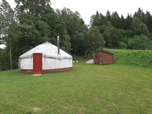 une grande tente blanche dans un champ avec une petite dans l'établissement Jurtos nuoma, à Kartena