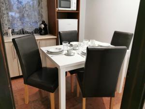 a table with black chairs and a white table with glasses on it at Ambient Thermal Apartman Gyula in Gyula