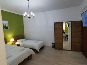 1 dormitorio con 2 camas, espejo y lámpara de araña en Ambient Deluxe Apartman, en Gyula