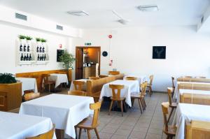 a restaurant with white tables and chairs and a kitchen at Villa Ombretta in Soraga