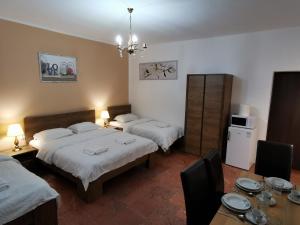 a bedroom with two beds and a table with chairs at Ambient Thermal Apartman Gyula in Gyula