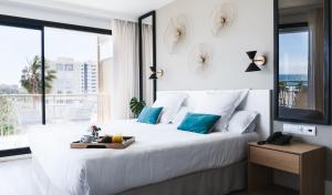 a bedroom with a large white bed with blue pillows at Hotel Almirante in Alicante