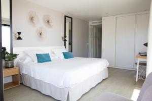 a white bedroom with a large white bed with blue pillows at Hotel Almirante in Alicante