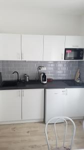 a kitchen with white cabinets and a chair in it at Domb Apartmanok in Sukoró