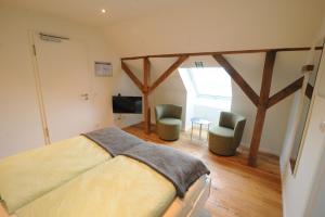 a bedroom with a bed and two chairs and a television at Blekkers Bed&Breakfast in Uelsen