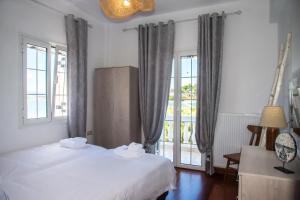 a bedroom with a white bed and a window at VILLA FRETTA in Corfu