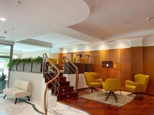 a waiting room with yellow chairs and a staircase at Hotel Ciudad de Compostela in Santiago de Compostela