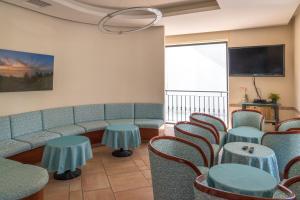a waiting room with a couch and tables and a tv at Hotel Tiglio in Rimini