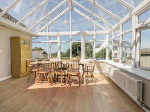 a conservatory with a table and chairs and windows at Auverne in Bude