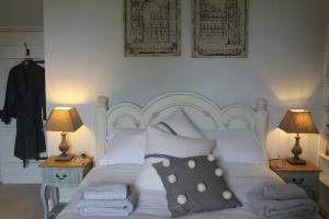 a bedroom with a white bed with pillows and two lamps at Roundhill Farmhouse in Bath