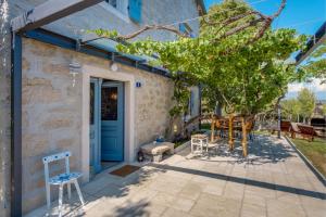 une terrasse avec une porte bleue et un arbre. dans l'établissement Villa Veli Dvor, à Nerezine