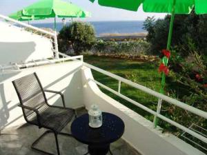 een balkon met een stoel, een tafel en een parasol bij Elpida Andros in Batsi