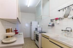 a white kitchen with a sink and a microwave at Ca l'Aurora, con vistas al mar y a la montaña in Caldes d'Estrac