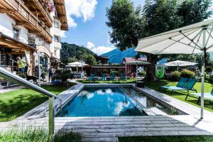 una piscina con un ombrellone accanto a un edificio di ALPENHOTEL TYROL - B&B - Hundefreundliches Konzepthotel - adults only a Pertisau