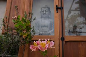 a bunch of pink flowers in front of a statue at La Cambra casa rural in Potríes