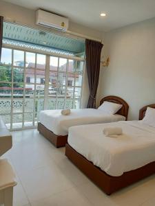 2 camas en una habitación de hotel con balcón en Promporn Boutique Hotel en Nan