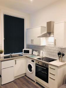 a kitchen with white cabinets and a washer and dryer at Albert Hottub & Jacuzzi Apartments in Blackpool