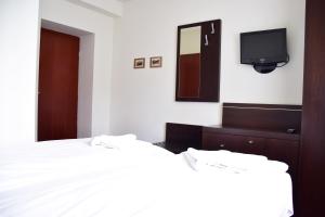 a bedroom with a white bed and a tv at Willa Halka in Zakopane