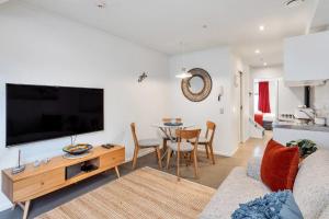 a living room with a couch and a tv and a table at Chic 3 Bedroom in the City Central I FREE PARKING in Auckland