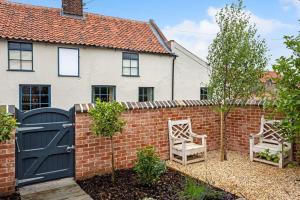 a house with a brick fence and two chairs at The Sail House in Wighton